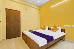 哥印拜陀SPOT ON Kayal Residency的一间卧室配有一张黄色墙壁和一扇门的床