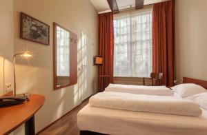 阿姆斯特丹A火车酒店的一间卧室设有两张床、一张桌子和一个窗口。