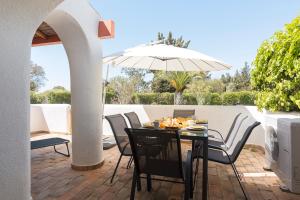 维拉摩拉Aldeia do Golfe - Private condominium by HD的庭院里配有桌椅和遮阳伞
