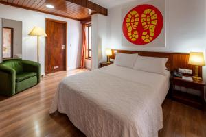 圣若昂达马德拉A. S.圣若昂-马德拉酒店的一间卧室配有一张大床和一张绿色椅子