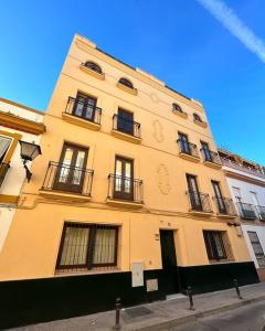 塞维利亚Casa Procurador Triana的一条高大的黄色建筑,街上有窗户