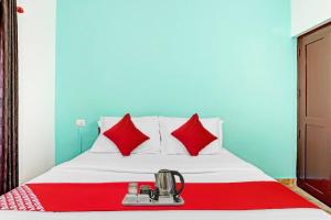 KazhakuttamOYO Bevis的一张带红色枕头的床和一张红色毯子上的搅拌机