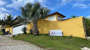 布希奥斯Pousada Mar'Tito Forno的黄色房子前面的棕榈树,有标志