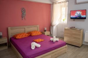 埃尔莫波利斯Maya Studio的一间卧室配有一张带紫色床单和橙色枕头的床