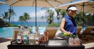 维雷亚茂宜岛维雷亚海滩万豪酒店&度假村的站在桌子前喝饮料的女人