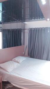 SunggalSkyview Setiabudi Apartment的卧室配有白色的床和灰色窗帘