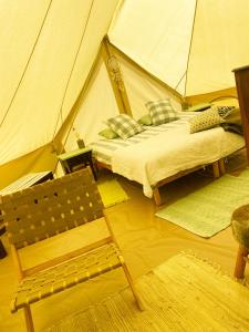 皮萨拉Glamping Bed and Breakfast Finca Alegria de la Vida的一间卧室配有一张床铺,帐篷内提供一把椅子