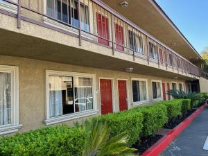 皮科里韦拉Rivera Inn & Suites Motel的前方有红色门和灌木的建筑