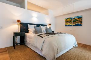 黑潭Oneroa Beach Apartment的一间卧室配有一张大床和一张带台灯的桌子