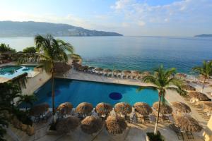 阿卡普尔科Las Torres Gemelas VIP的享有带遮阳伞的游泳池和大海的景致。