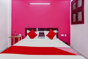 加济阿巴德Super OYO The Prima Residency的粉红色的卧室配有白色的床和红色枕头