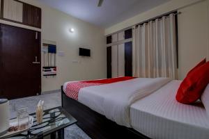巴特那Super OYO Flagship Rajbanshi Nagar的一间卧室配有一张床、一张桌子和一台电视。