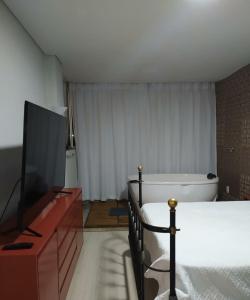新利马Loft Espaço Vila da Serra的一间卧室配有一张床、一台电视和一个浴缸