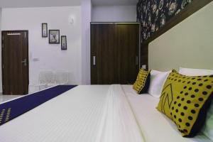 齐拉克普尔SPOT ON Hotel White Rose的一间卧室配有一张大床,提供黄色和蓝色的枕头