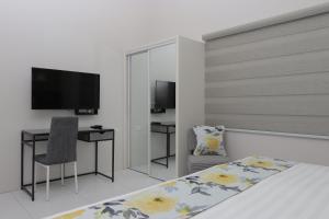 西班牙港Kiskadee Korner的一间卧室配有一张床、一张书桌和一台电视
