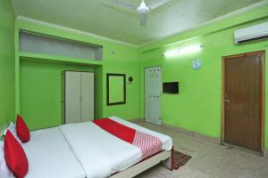 布巴内什瓦尔OYO Near Kalinga Hospital的一间卧室设有绿色的墙壁和一张带红色枕头的床