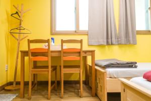 大邱大邱中城旅舍的配有桌子和两把椅子及一张床的房间