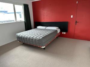 罗托鲁瓦MALFROY Motor Lodge Rotorua的红色墙壁的房间里一张床位