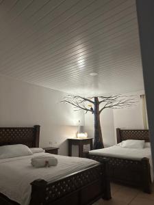 阿拉胡埃拉Hotel Pacande B&B的卧室配有两张床,墙上有一棵树
