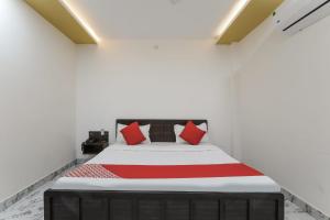 BijnaurHotel O Aastha Near Chaudhary Charan Singh International Airport的一间卧室配有一张带红色枕头的大床