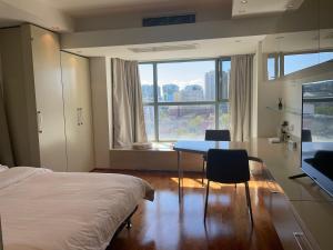北京Beijing Elegant Seasons Park Apartment的一间卧室配有一张床、一张桌子和一个窗户。