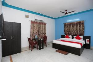 BāliantaOYO Maa Banadurga Guest House的卧室配有一张床和一张桌子及椅子