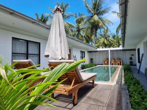 吉利特拉旺安吉利卡哈阳甘别墅度假村的一个带遮阳伞和椅子的庭院和一个游泳池