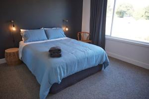 克莱斯韦克Enjoy a renovated retreat with outdoor bath的一间卧室配有一张带蓝色床单的大床和窗户。