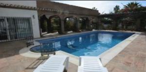 贝纳尔马德纳espectacular villa puerto marina playa的旁边设有2把白色椅子的大型游泳池