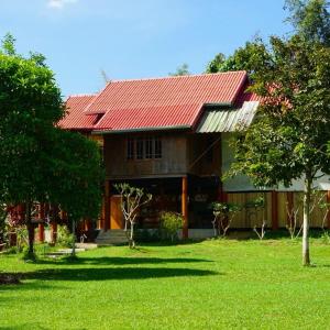 塞友BaanRai KhunYa บ้านไร่คุณย่า的绿色庭院中一座红色屋顶的房子