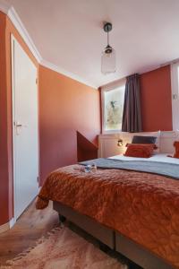 法尔肯堡Hotel Janssen的一间卧室配有一张带橙色墙壁的大床