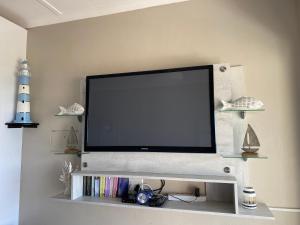 马盖特Uvongo Chalet 11的客厅的架子上配有平面电视
