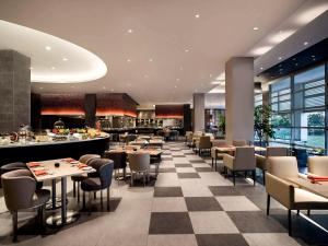 米里普尔曼美里海滨酒店的餐厅设有桌椅和 ⁇ 板地板