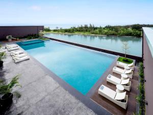 米里普尔曼美里海滨酒店的一座游泳池,位于一座带椅子和水的建筑中