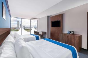 普埃布拉Wyndham Puebla Angelopolis的酒店客房设有两张床和电视。