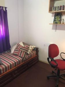 坦迪尔Habitacion Super Comoda en Casa Particular的一间卧室配有一张床和一张红色椅子
