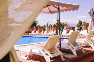 普里兹伦Nafron Hotel的游泳池旁的一排椅子和遮阳伞