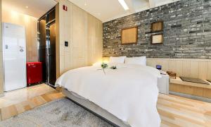 大邱Hotel Yeogiuhtte SeoDaegu的卧室配有白色大床和砖墙