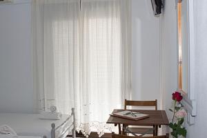 斯基亚索斯镇La Pensione Skiathos的一间卧室配有一张床、一张桌子和一个窗户。