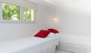德尼亚MR Hotelet de la Raconà & Apartments的白色卧室,床上配有红色枕头