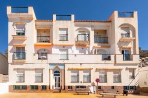 MelicenaApartamento junto al mar en costa tropical y Alpujarras granadinas的带阳台的建筑,前面设有长凳