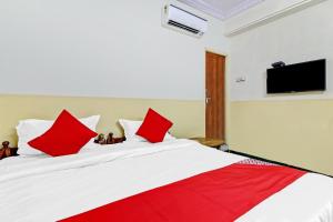 瓦朗加尔OYO Suraj Residency的卧室配有带红色枕头的大型白色床