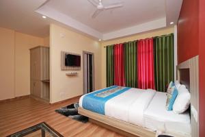 达兰萨拉OYO Hotel Chandni的一间卧室配有一张带彩色窗帘的床和电视。