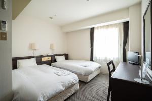 神户Hotel Casabella Inn Kobe的酒店客房配有两张床和一张书桌