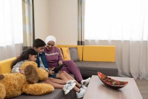 迪拜迪拜世贸中心诺富特酒店的两个女孩和一个女人坐在一张长着泰迪熊的沙发上