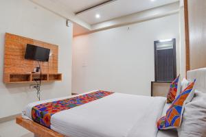 PrayagrajFabHotel Bliss Inn的一间卧室配有一张床,墙上配有电视