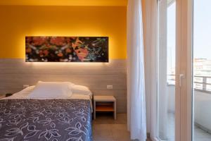 佩萨罗可利佩酒店的卧室配有一张床,墙上挂有绘画作品