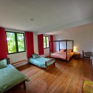 Vallombre natiora的一间卧室设有两张床和红色窗帘