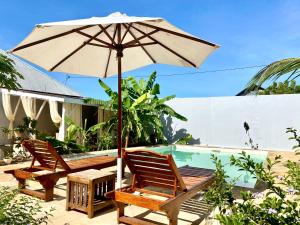 Banda KuuMaisha Villa Nungwi的一个带两把椅子和一把遮阳伞的庭院,毗邻一个游泳池