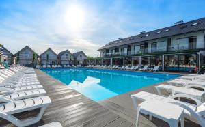 格里兹鲍Holiday Park & Resort Grzybowo的一座带白色躺椅的游泳池,位于大楼旁